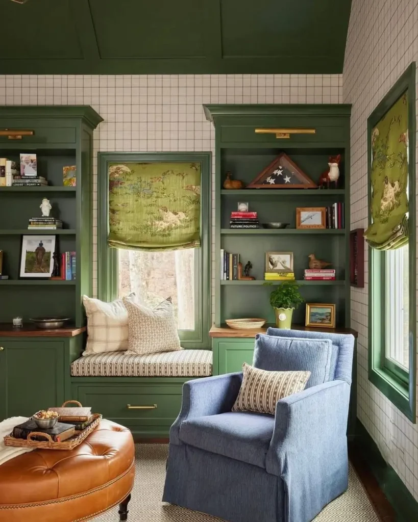 Traditional study with cozy olive green built-in bookshelves, window seat, and grid-patterned wallpaper.