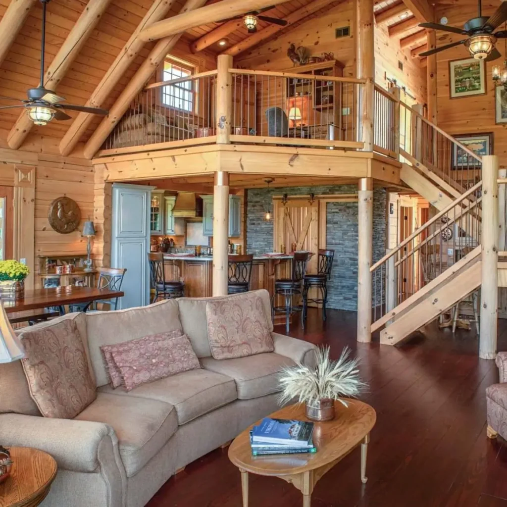 Open-concept log cabin living space with connected kitchen and loft.