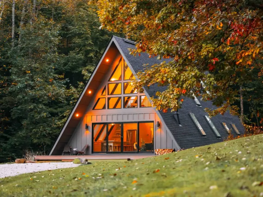 A classic A-frame cabin in Hocking Hills with a glowing wall of windows at dusk.