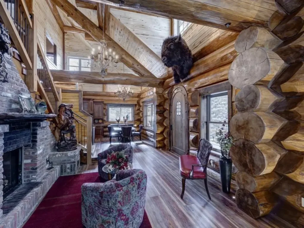 Spacious log cabin interior with high ceilings, exposed logs, and brick fireplace.