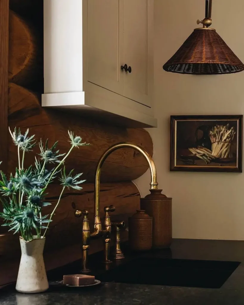 Log cabin kitchen with brass faucet, woven pendant light, and fresh greenery.