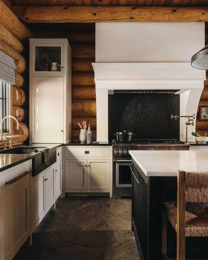 Modern log cabin kitchen with white cabinets and dark countertops.