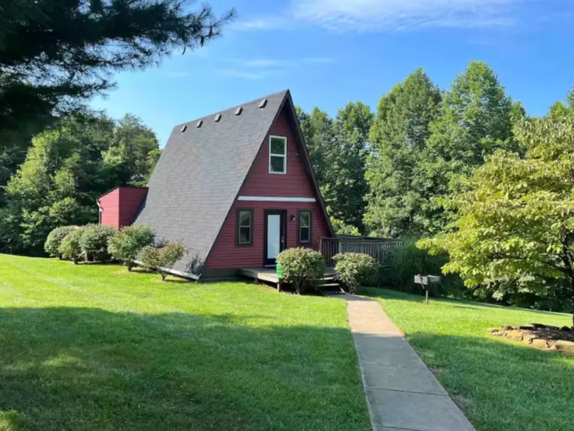 A classic red A-frame cabin in Ohio with a tidy lawn and a welcoming front path.