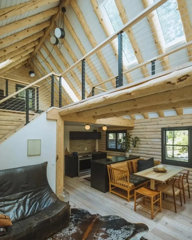 Open-concept log cabin interior with high ceilings, exposed logs, and modern kitchen.