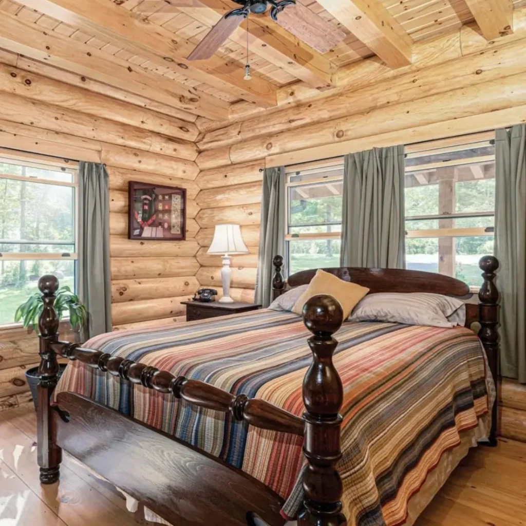 Classic log cabin bedroom with wooden bed, striped quilt, and rustic walls.