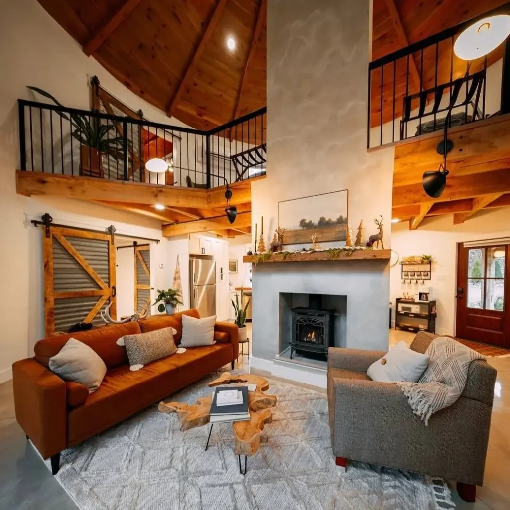 The soaring interior of a grain silo house living room with an exposed wood ceiling and central fireplace.