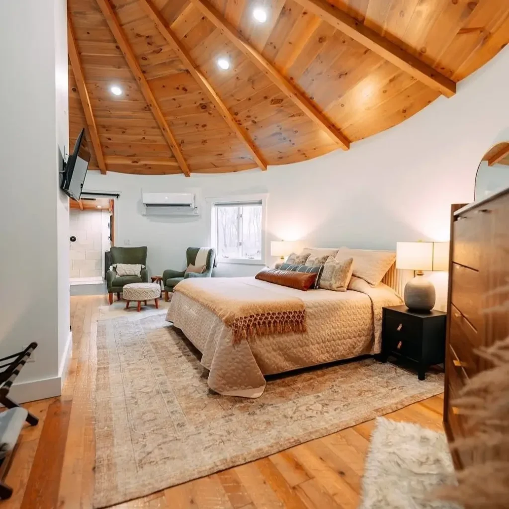 A serene bedroom situated on the upper loft level of the grain silo with a stunning curved wood ceiling.