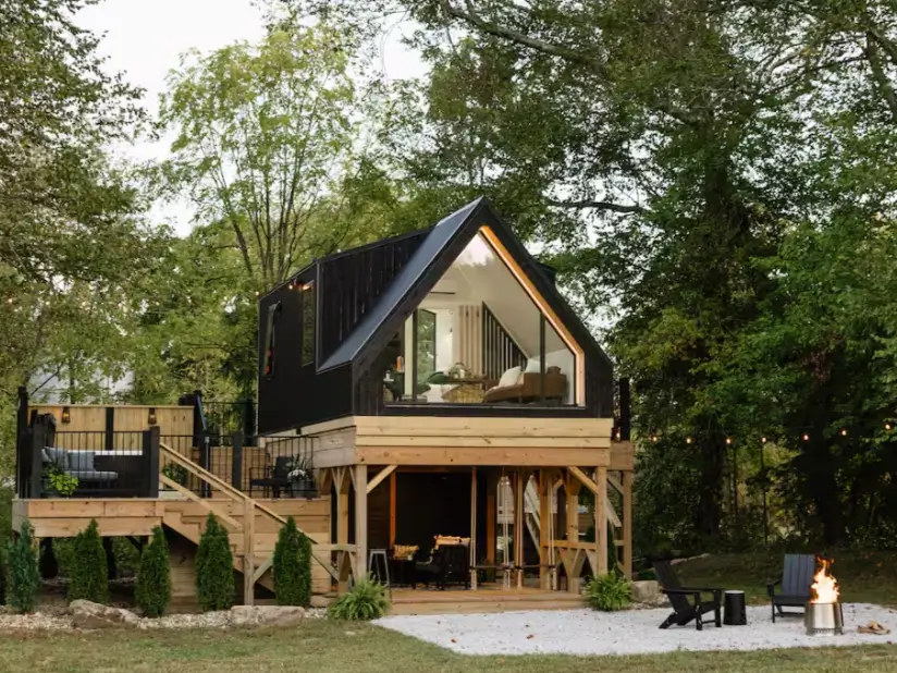 A striking black A-frame cabin in Hocking Hills with a multi-level deck and a modern fire pit, showcasing the best of outdoor living.
