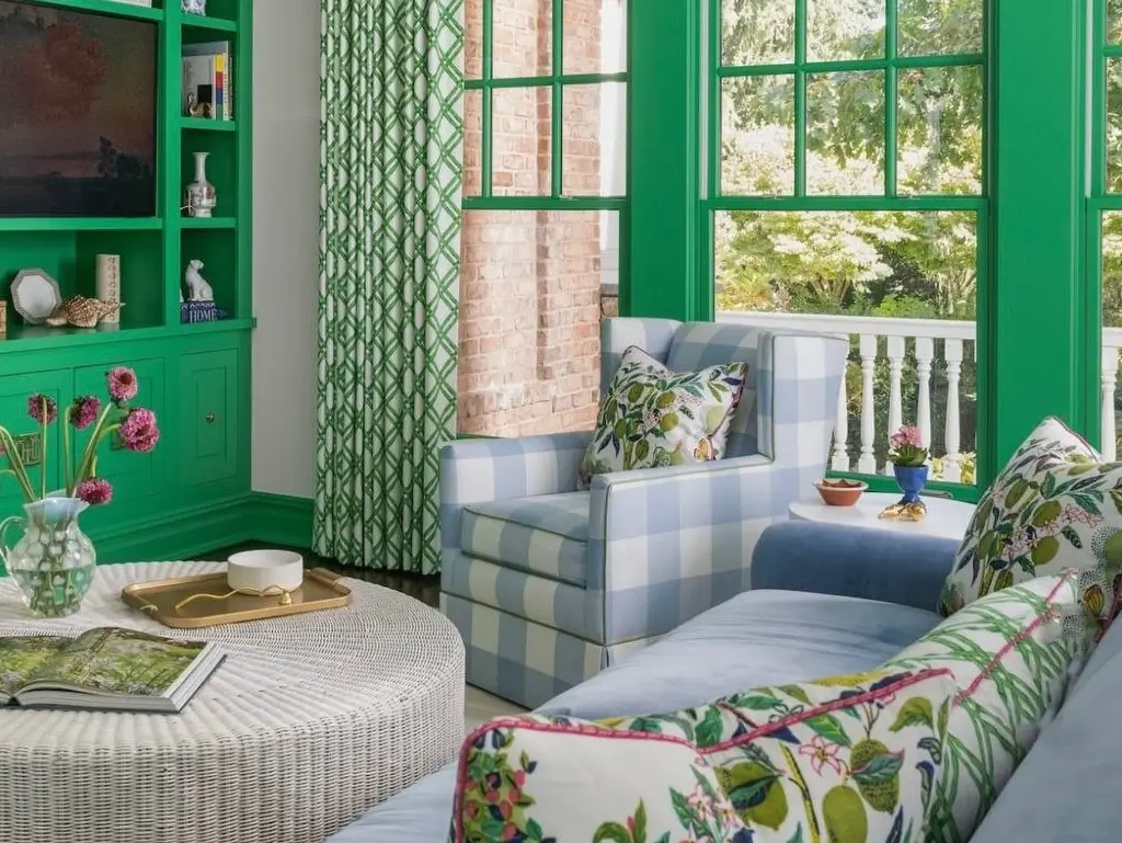 Vibrant Kelly green interior house paint colors used on living room built-ins and window trim, with a blue gingham armchair and colorful patterned textiles.