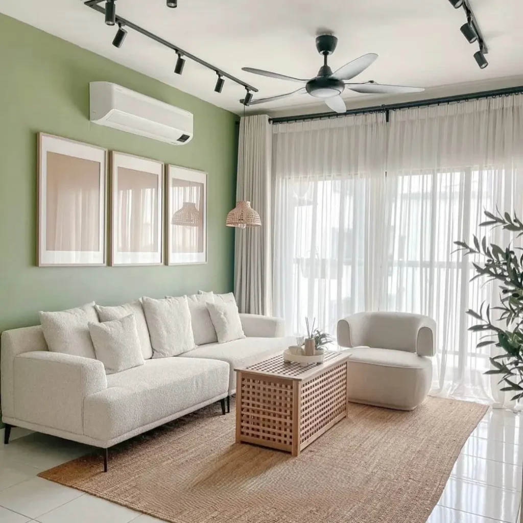 A living room with a sage green accent wall, part of a small apartment design idea on a budget, featuring a white sofa and natural wood accents.