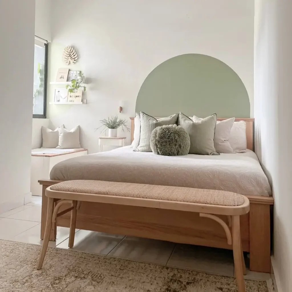 A bedroom with a sage green painted arch on the wall behind the bed, a simple small apartment decorating idea.