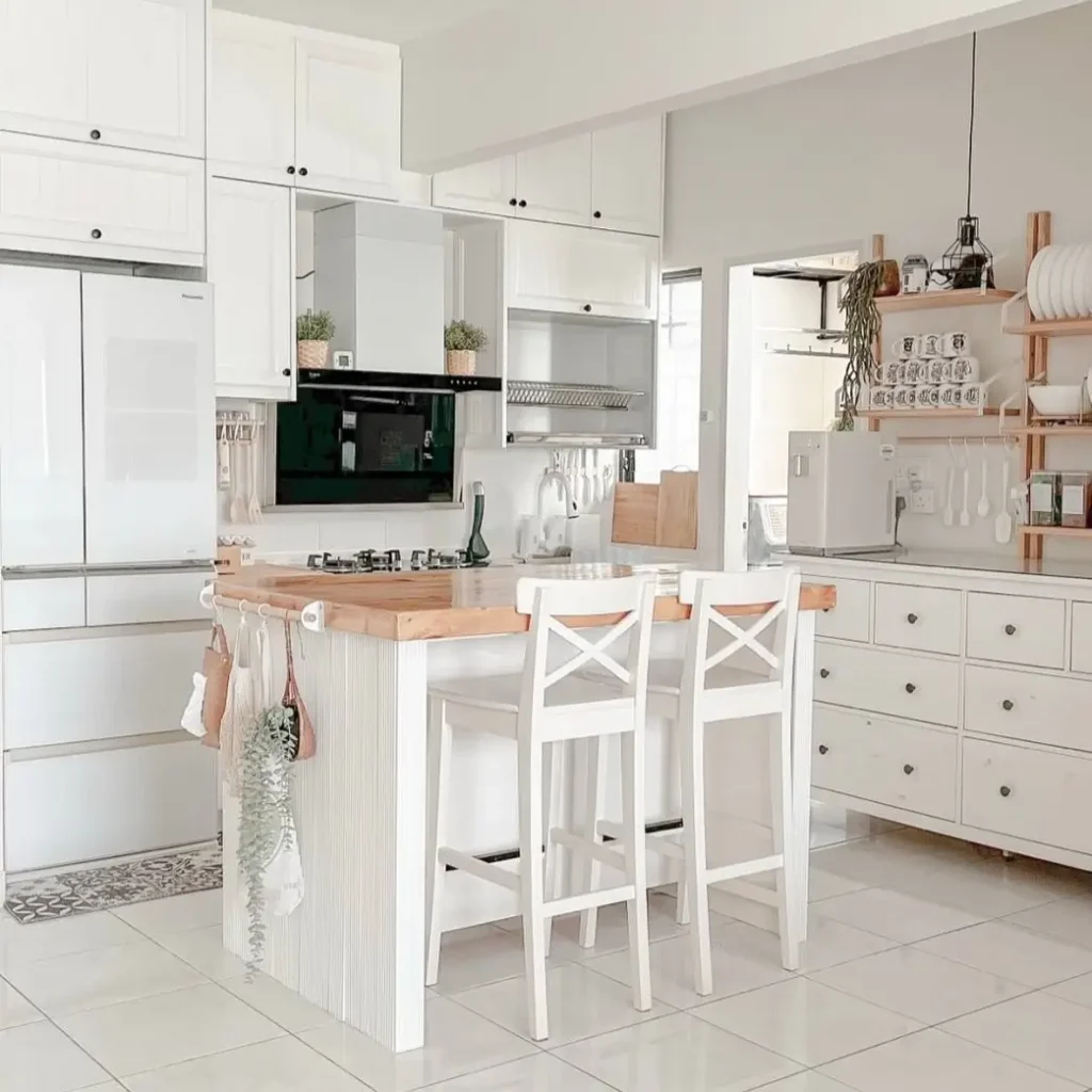 A white kitchen island with a wood top serves as a dining table, a practical small apartment design idea on a budget.