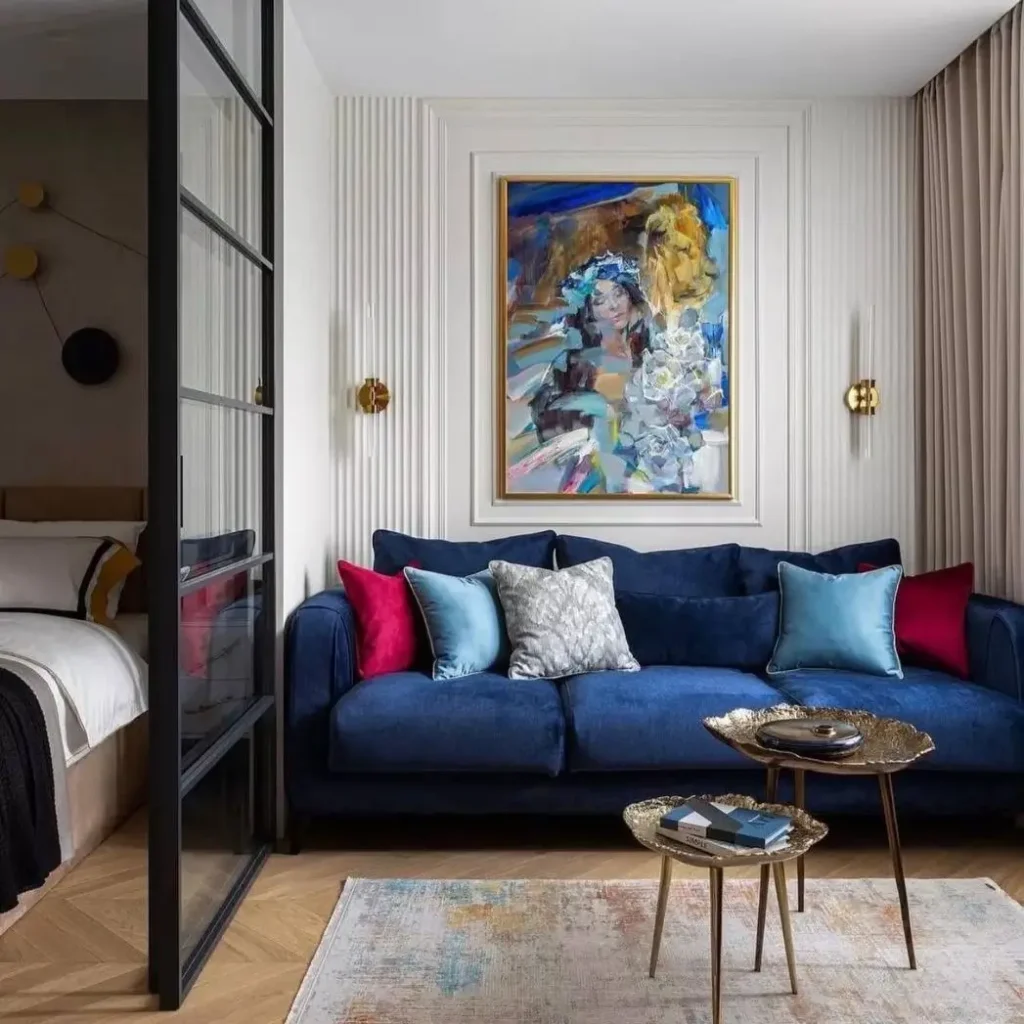A living room separated from a bedroom by a black-framed glass partition, a stylish small apartment design idea.