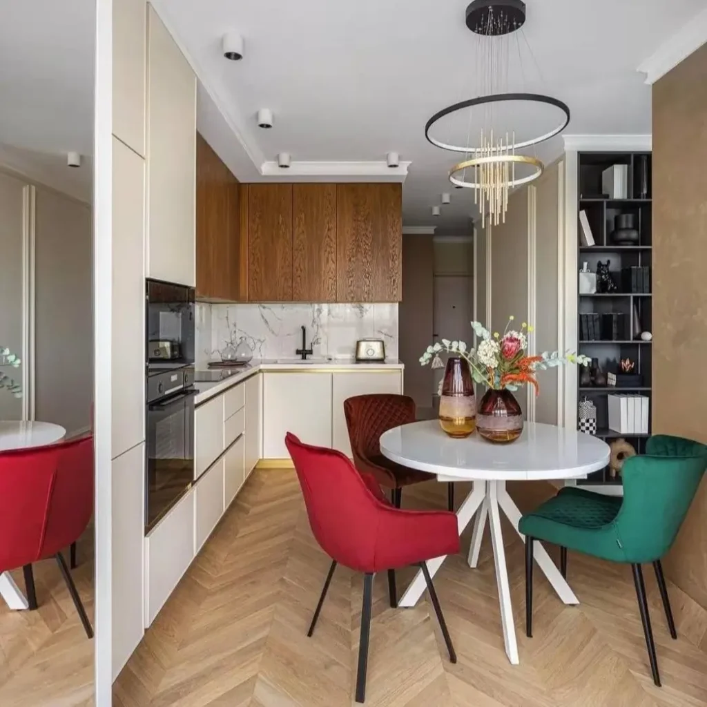 A dining area with a mirrored wall reflecting colorful chairs, a clever small apartment decorating idea on a budget.