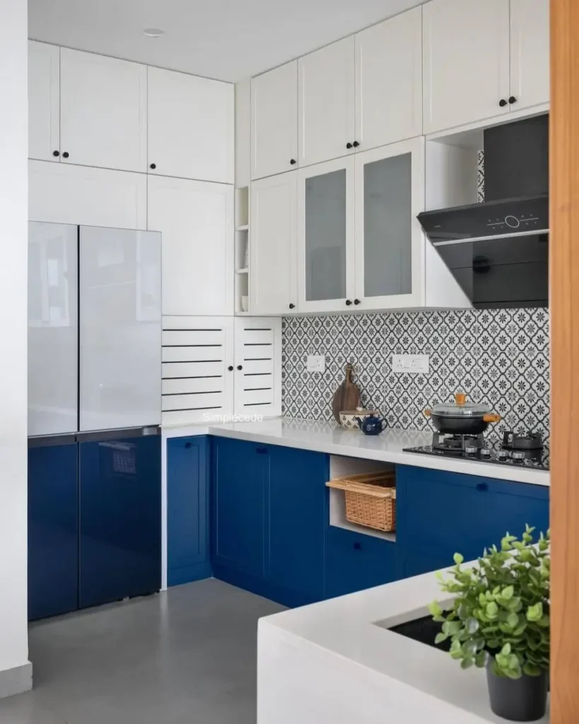 A compact kitchen featuring one of the best small apartment decorating ideas on a budget: bold blue lower cabinets paired with classic white uppers.