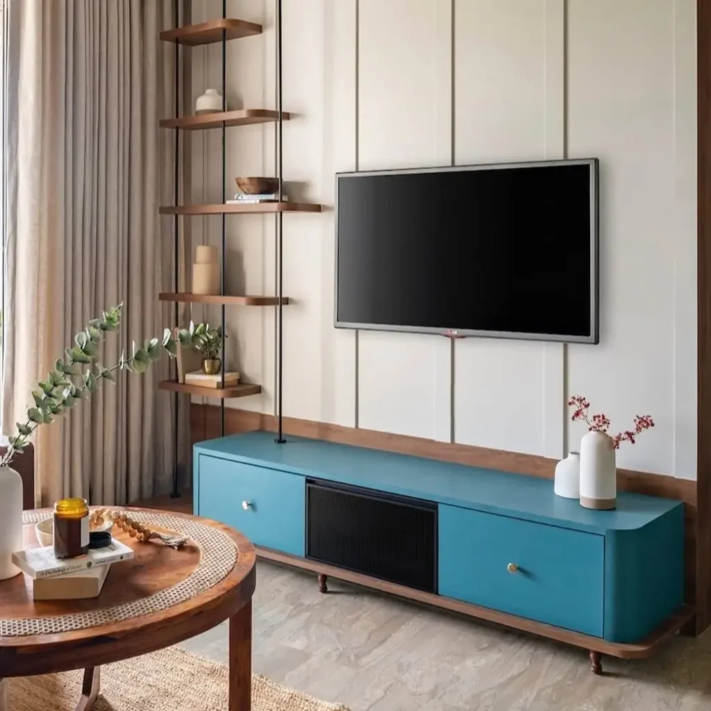 A living room with a blue floating media console and tension-rod shelving, a clever small apartment decorating idea on a budget.